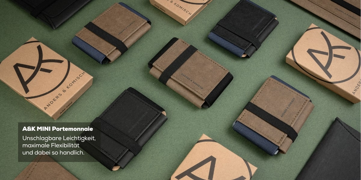 Viele A&K MINI Portemonnaies in den Farben: Schwarz, Braund und Grau mit einer plastikfreien, nachhaltigen Verpackung.